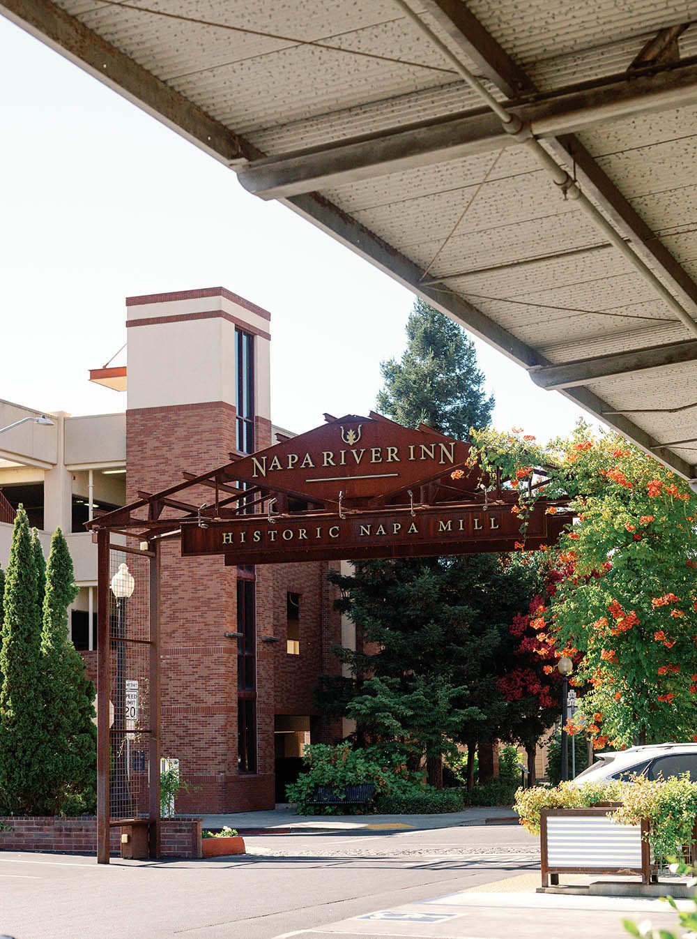 Front entrance porte-cochère of Napa River Inn at the Historic Napa Mill, with the carved Napa River Inn and Historic Napa Mill sign over the brick driveway.